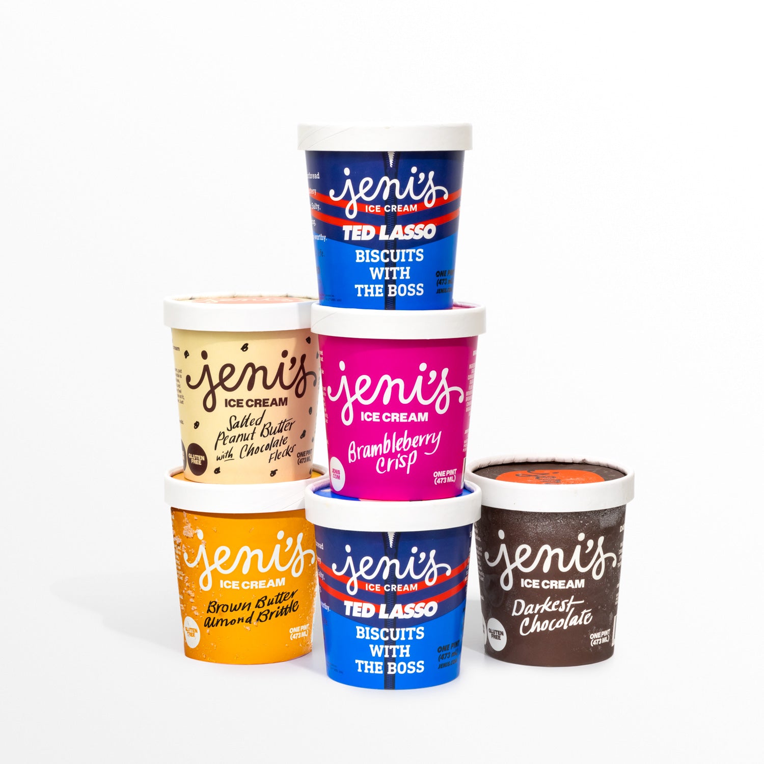 Six pints of Jeni's Splendid Ice Creams arranged in a pyramid on a white background, including two navy Ted Lasso 'Biscuits with the Boss' pints, plus Salted Peanut Butter with Chocolate Flecks, Brambleberry Crisp, Brown Butter Almond Brittle, and Darkest Chocolate.